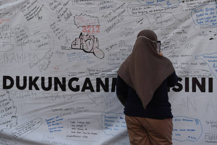 ANTARA FOTO/Wahyu Putro A Sejumlah warga mengamati tulisan yang ditujukan kepada tenaga medis di depan Wisma Atlet Jakarta