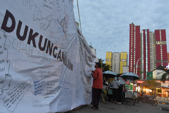 ANTARA FOTO/Wahyu Putro A Sejumlah warga mengamati tulisan yang ditujukan kepada tenaga medis di depan Wisma Atlet Jakarta