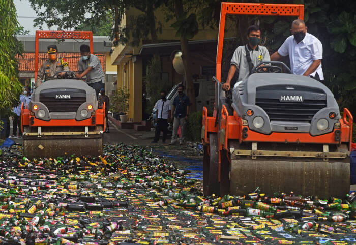 ANTARA FOTO/Asep Fathulrahman Petugas dengan menggunakan alat berat memecahkan ribuan botol miras (minuman keras) ilegal untuk dimusnahkan di halaman Mapolda Banten