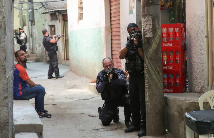 REUTERS/Ricardo Moraes Polisi mengarahkan senjata mereka selama operasi melawan pengedar narkoba di permukiman kumuh Jacarezinho di Rio de Janeiro