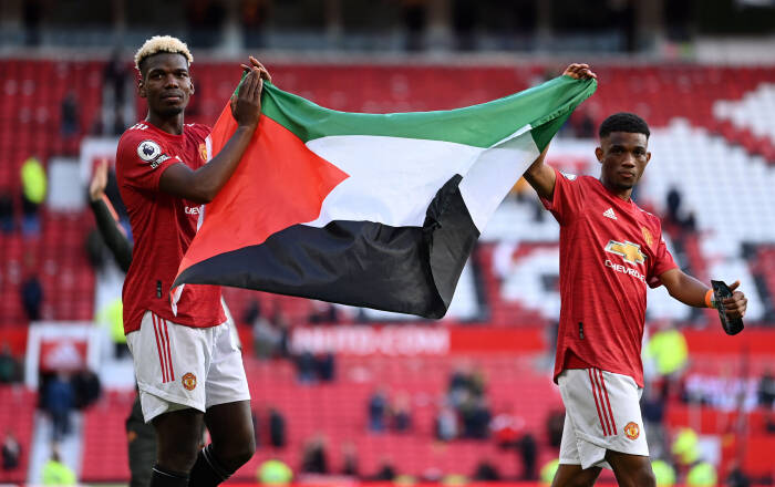 Paul Pogba dari Manchester United memberi tepuk tangan kepada para penggemar sambil memegang bendera Palestina bersama Amad Diallo selama lap penghargaan usai pertandingan