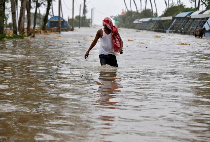 Seorang pria mengarungi jalan yang dipenuhi air (REUTERS/Rupak De Chowdhuri) Seorang pria mengarungi jalan yang dipenuhi air