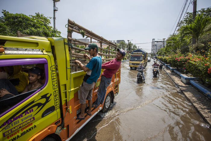 Warga menumpang truk saat melintasi banjir rob