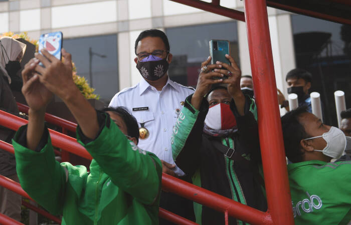 Gubernur DKI Jakarta Anies Baswedan melayani permintaan swafoto pengemudi ojek daring usai memantau titik penyekatan baru (ANTARA FOTO/Akbar Nugroho Gumay) Gubernur DKI Jakarta Anies Baswedan melayani permintaan swafoto pengemudi ojek daring usai memantau titik penyekatan baru
