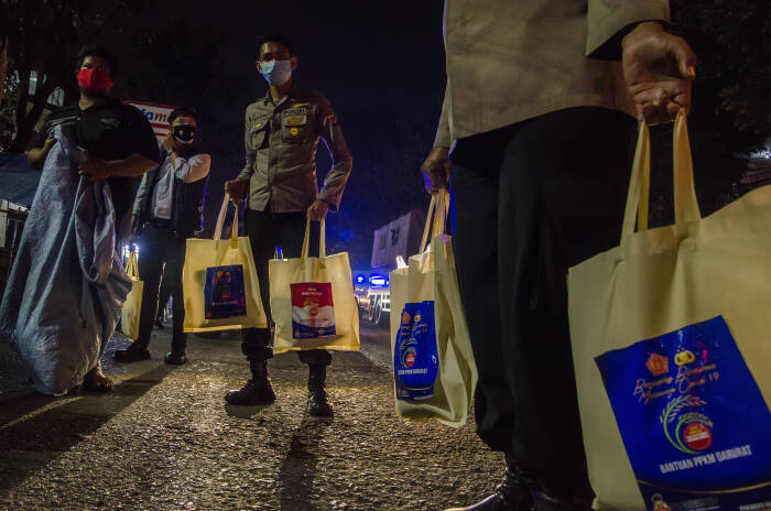 Anggota Kepolisian membawa bantuan sosial sembako untuk diberikan kepada seorang pemulung (ANTARA FOTO/Novrian Arbi) Anggota Kepolisian membawa bantuan sosial sembako untuk diberikan kepada seorang pemulung
