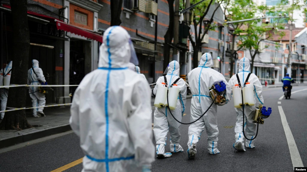 Petugas mengenakan pakaian hazmat saat melakukan penyiraman disinfektan di kawasan perumahan yang terkena lockdown di Shanghai, China, pada 15 April 2022. (Reuters/Aly Song)